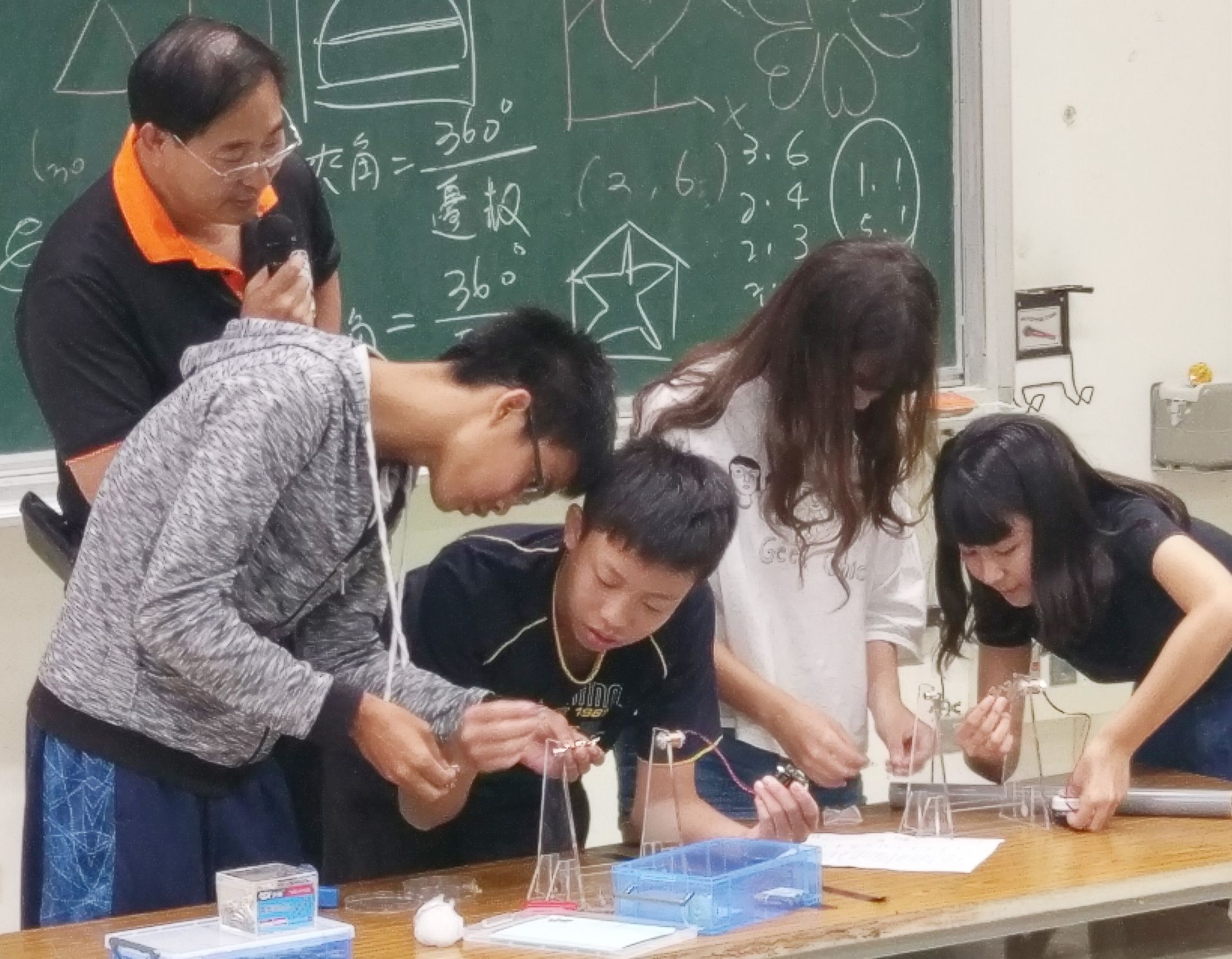 洪偉清教授（左一）悉心指導志工運用科學技巧，在學員們親身練習的過程中，了解科學營時如何帶領學童玩科學闖關遊戲。