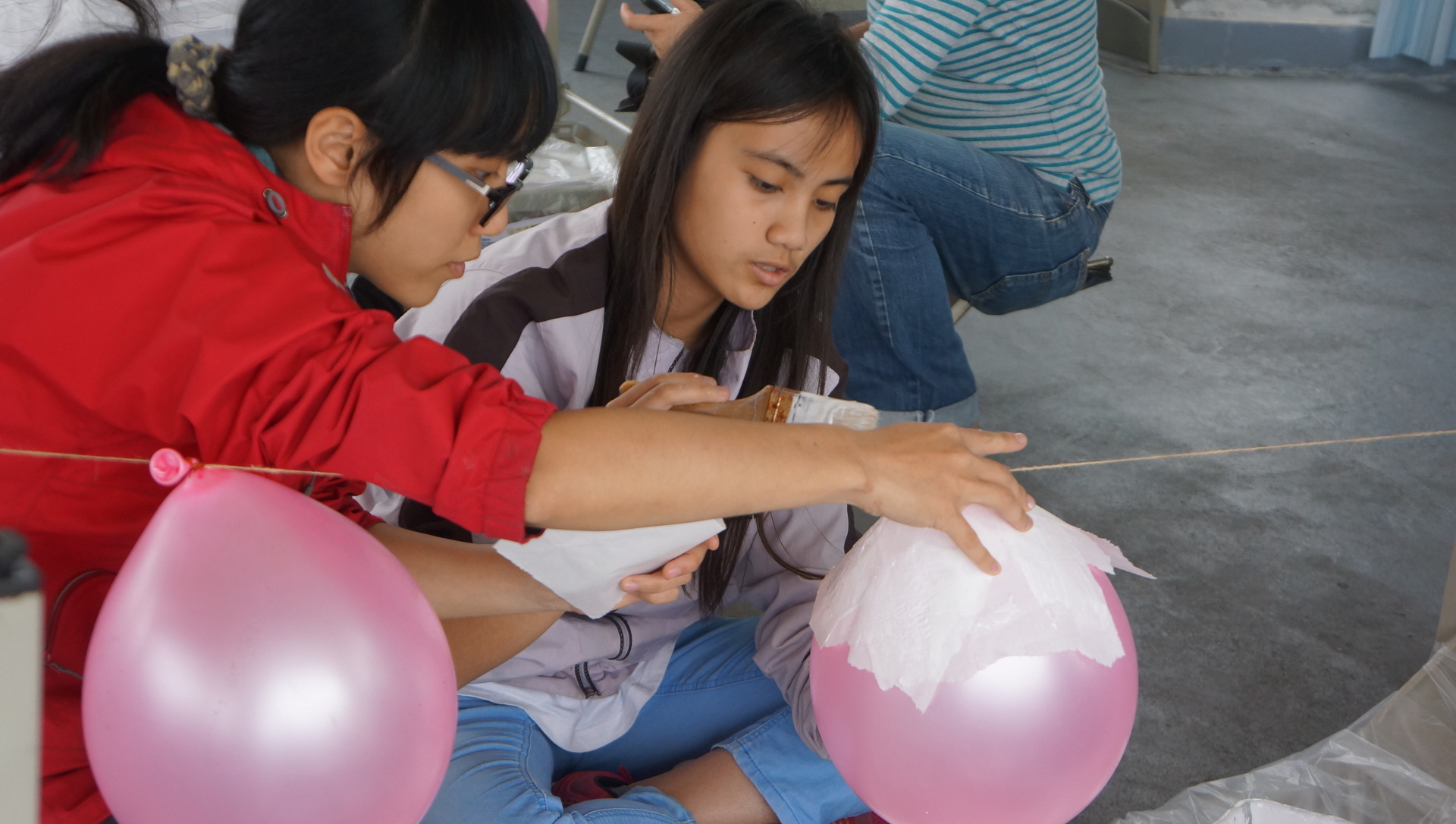 孩子們仔細溫柔地刷上白膠將宣紙與氣球結合
