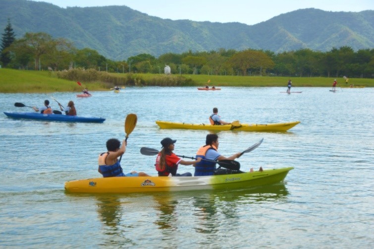 來賓及國際生駕駛獨木舟徜徉在東湖，映襯藍天白雲及綠野青山